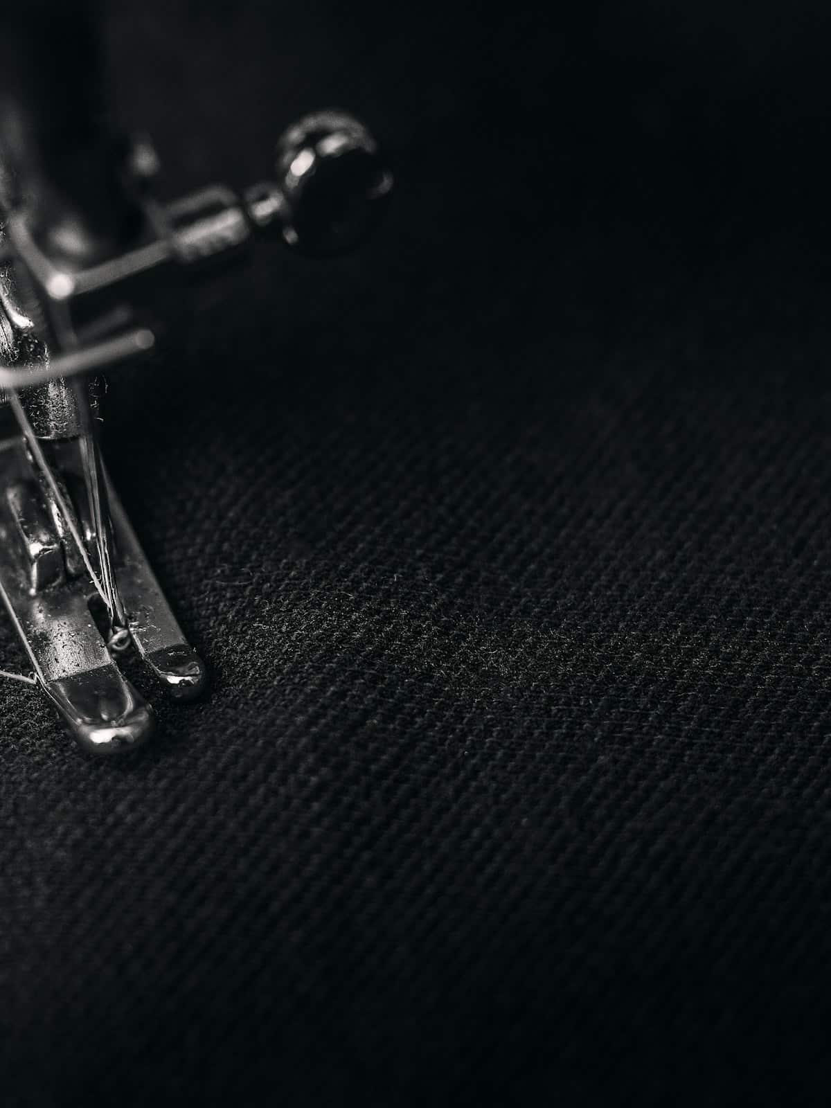 Close-up of a sewing machine stitching dark tailoring cloth