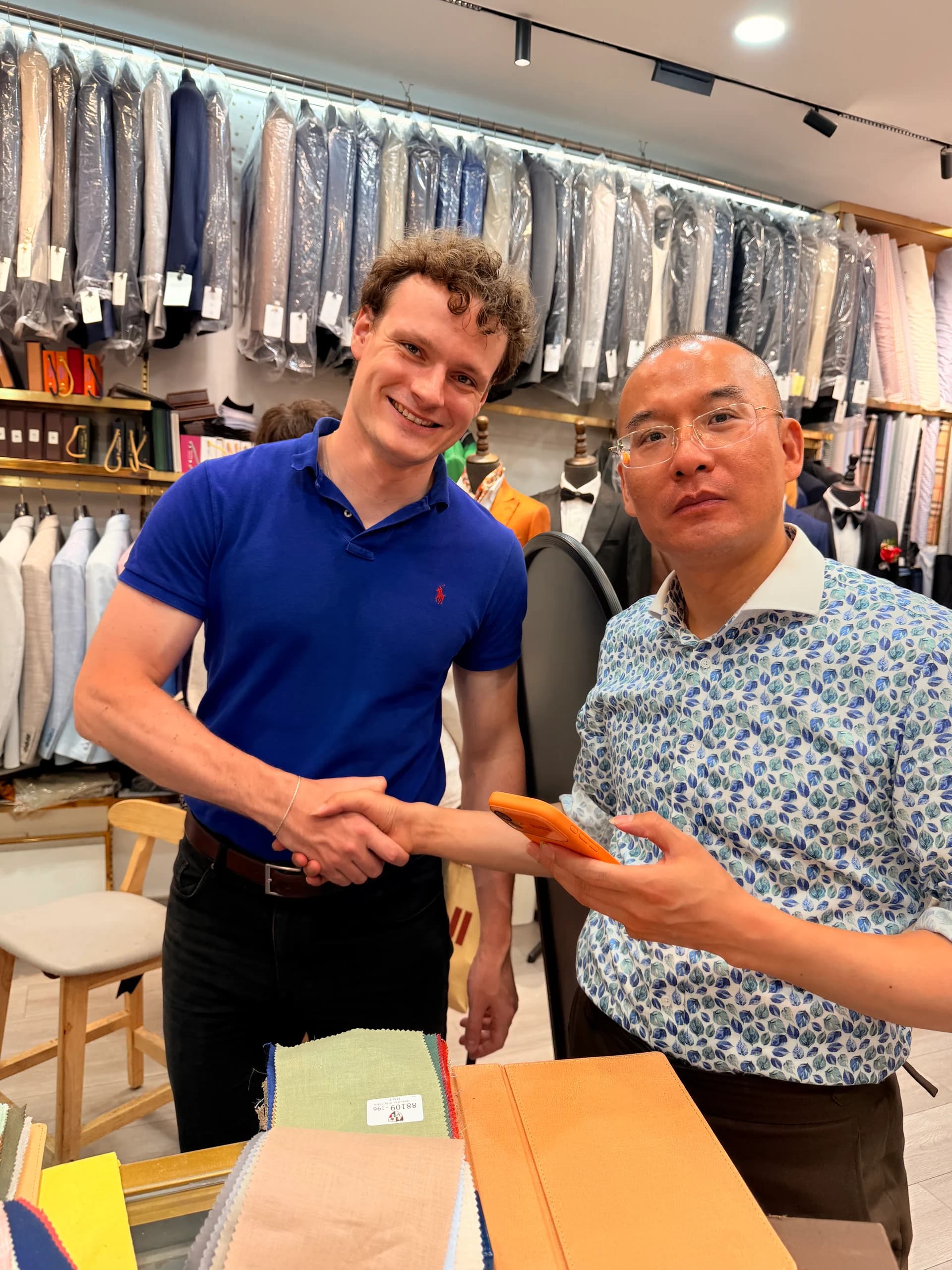 Client and Shanghai fabric market tailor shaking hands after reviewing fabric swatches