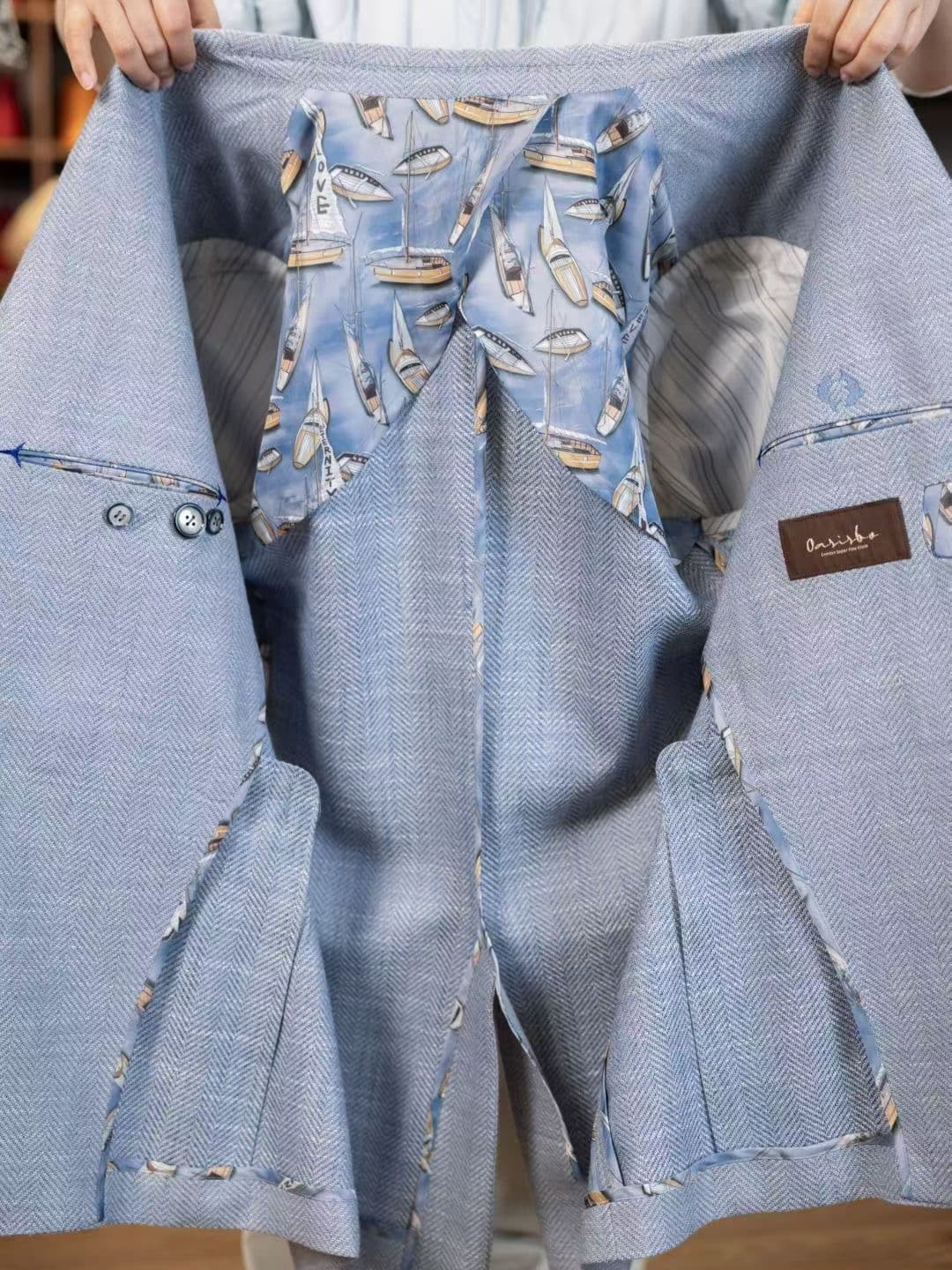 Opened light-blue herringbone jacket showing its patterned lining, inside pockets, and internal finishing