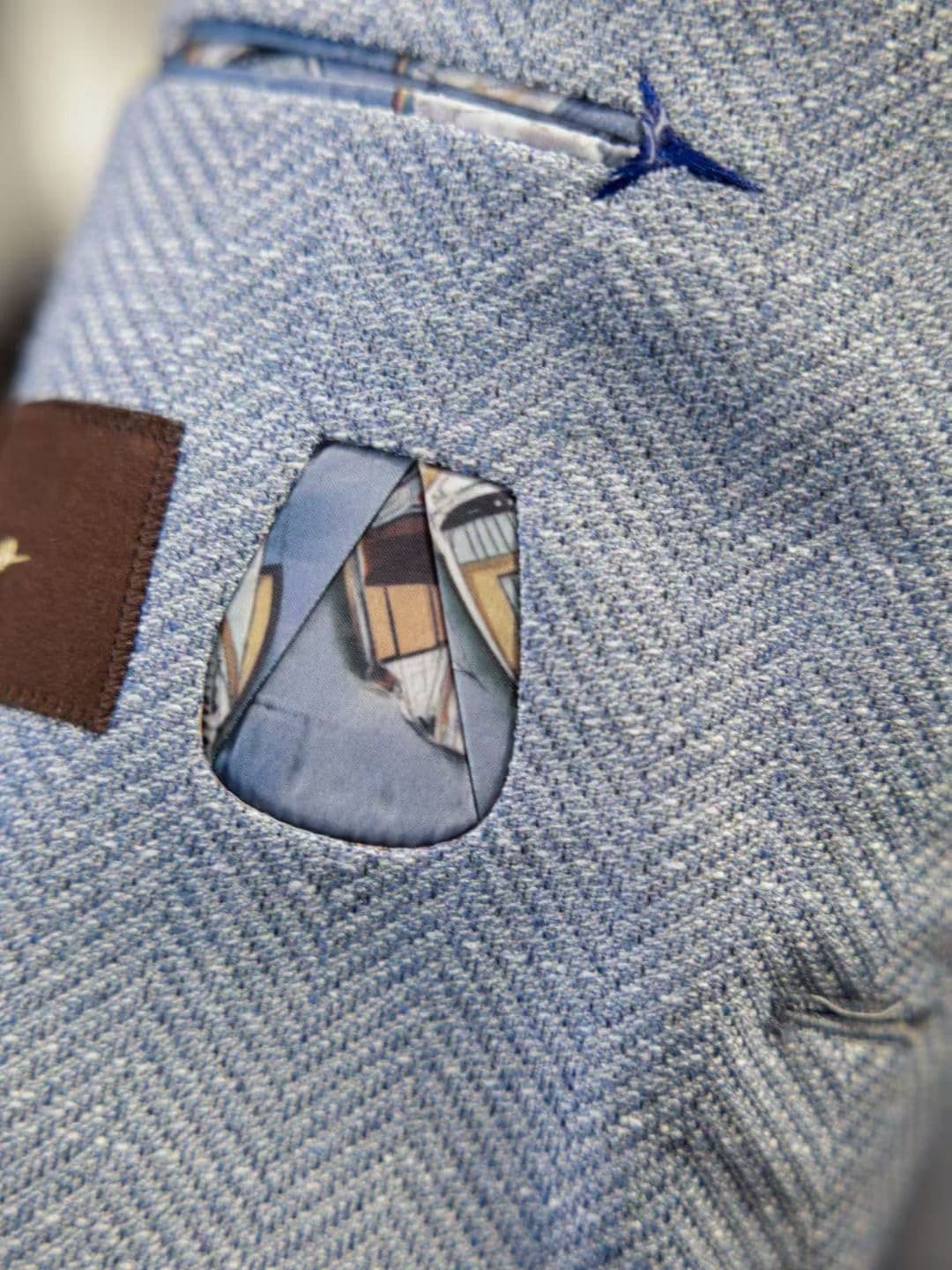 Close detail of a light-blue herringbone custom jacket pocket with patterned lining trim
