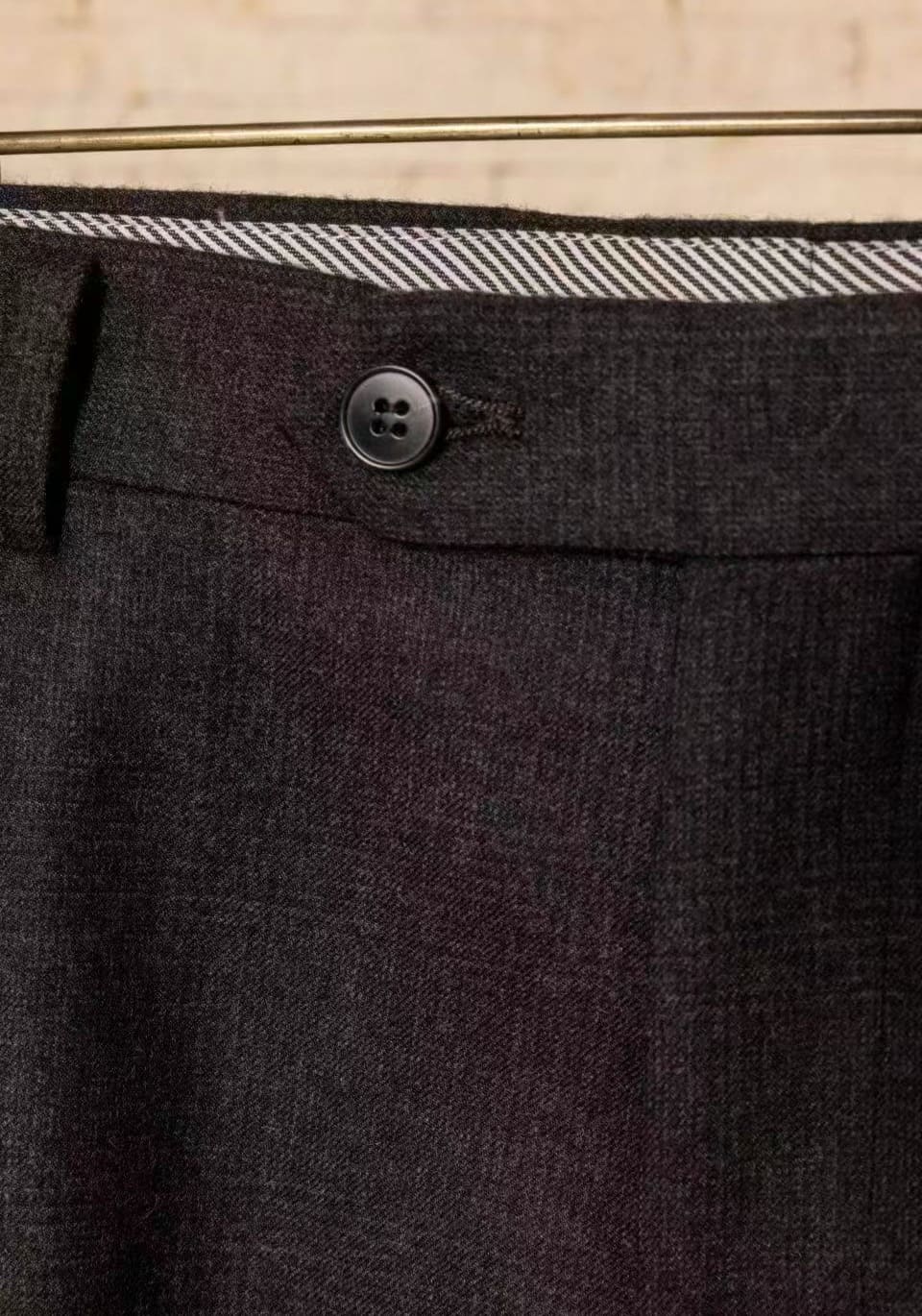 Bund einer anthrazitbraunen Maßhose mit Knopf und gemusterter Innenkante