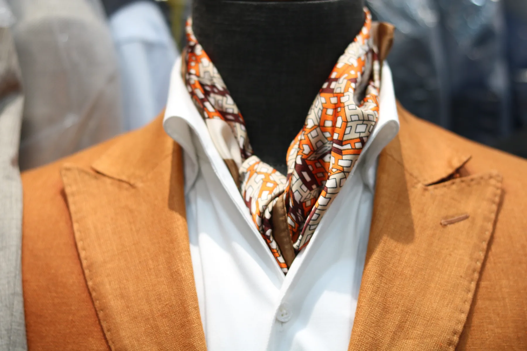Orange jacket with a notched lapel, white shirt and patterned scarf