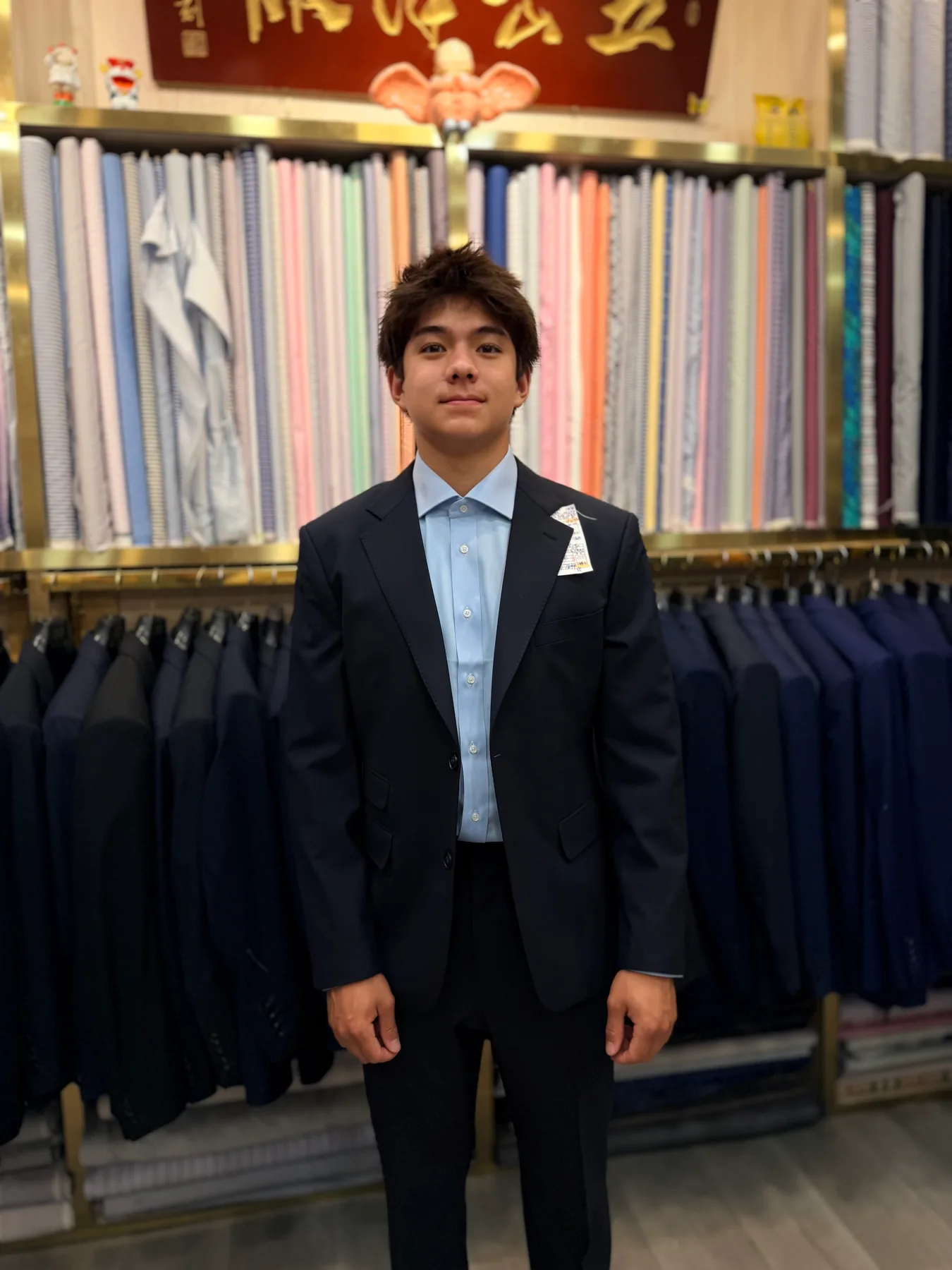 Front view of a young American client in a navy suit with notch lapels and a pale-blue shirt