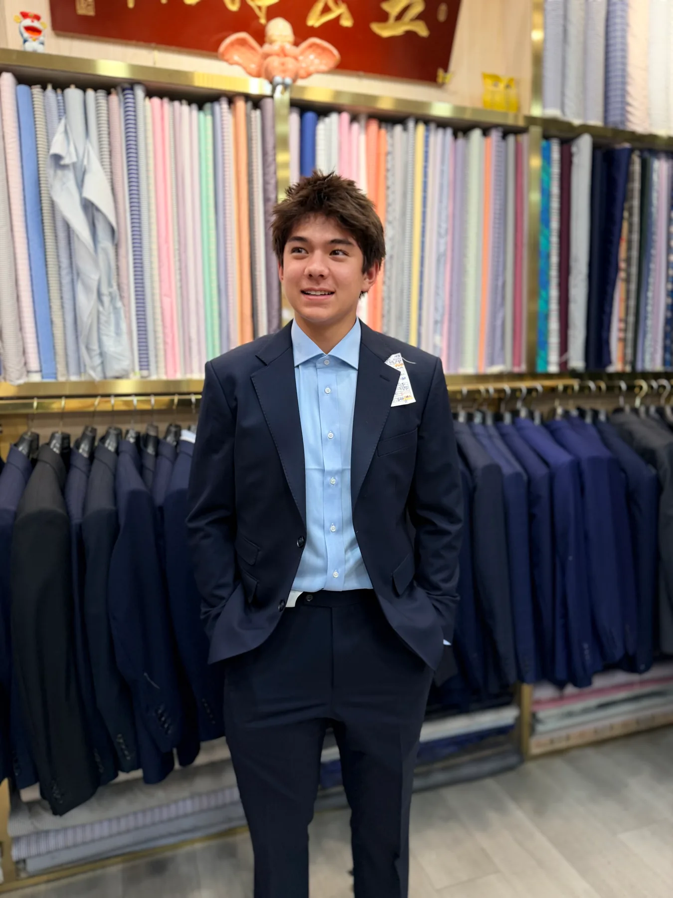 Young American client posing with hands in trouser pockets in a navy two-piece suit