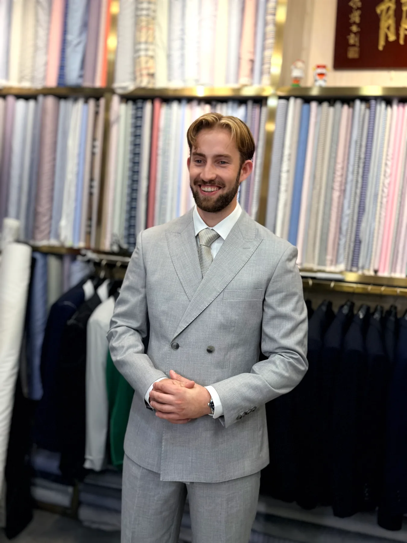 Client smiling in a light-colored double-breasted suit inside Wuyue