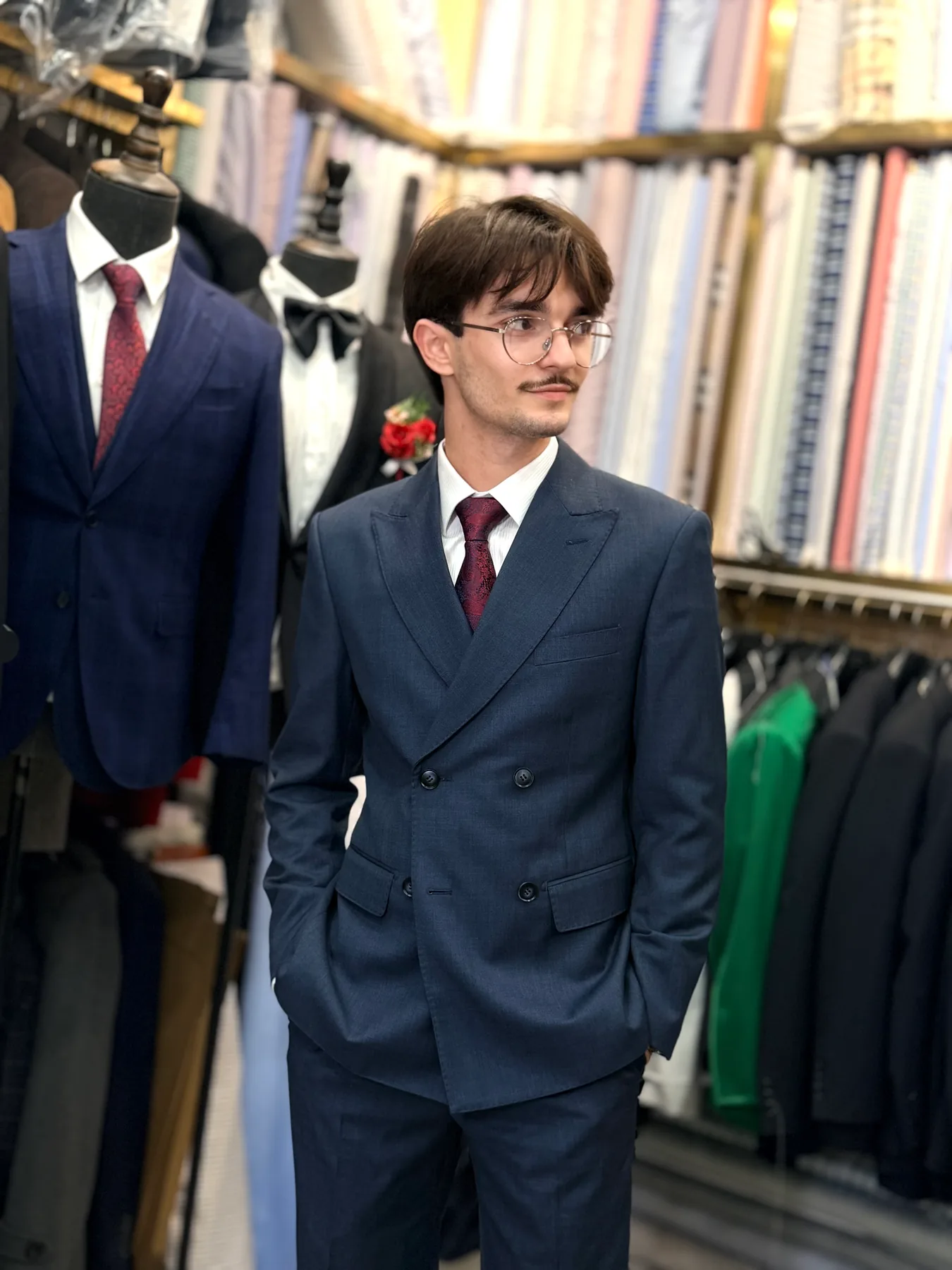 Client posing with one hand in a trouser pocket in a navy double-breasted suit