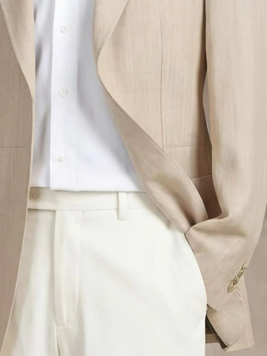 Close-up of a light beige custom suit jacket worn with a white shirt and ivory trousers