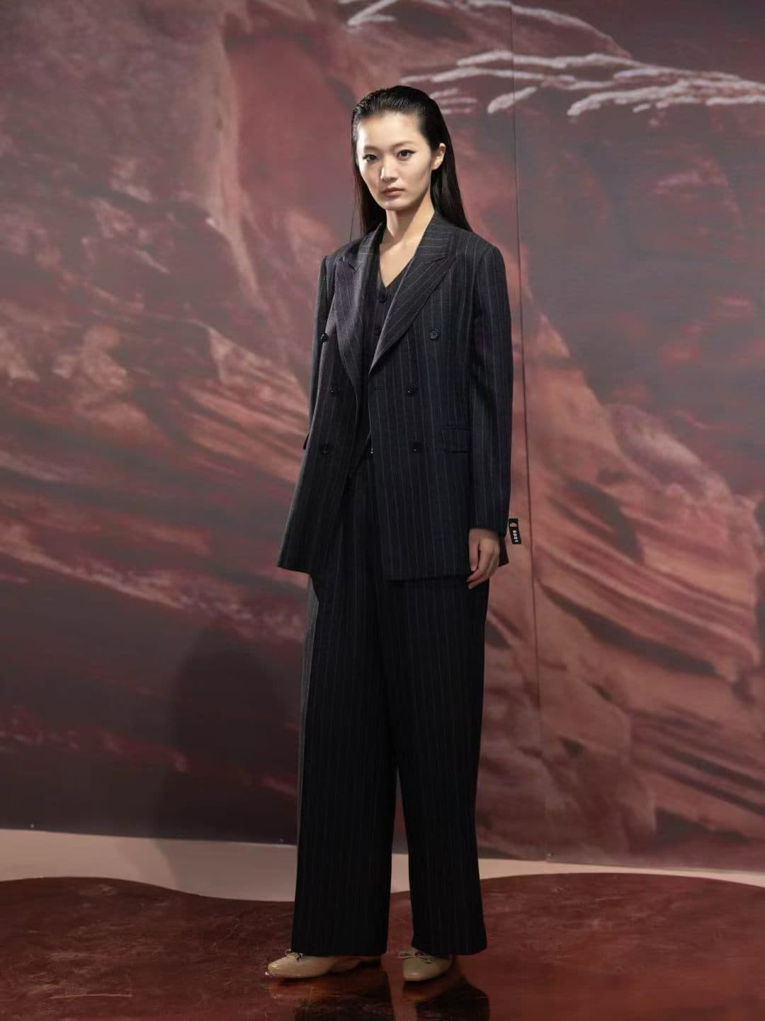 Woman wearing a dark pinstripe double-breasted pantsuit with wide-leg trousers
