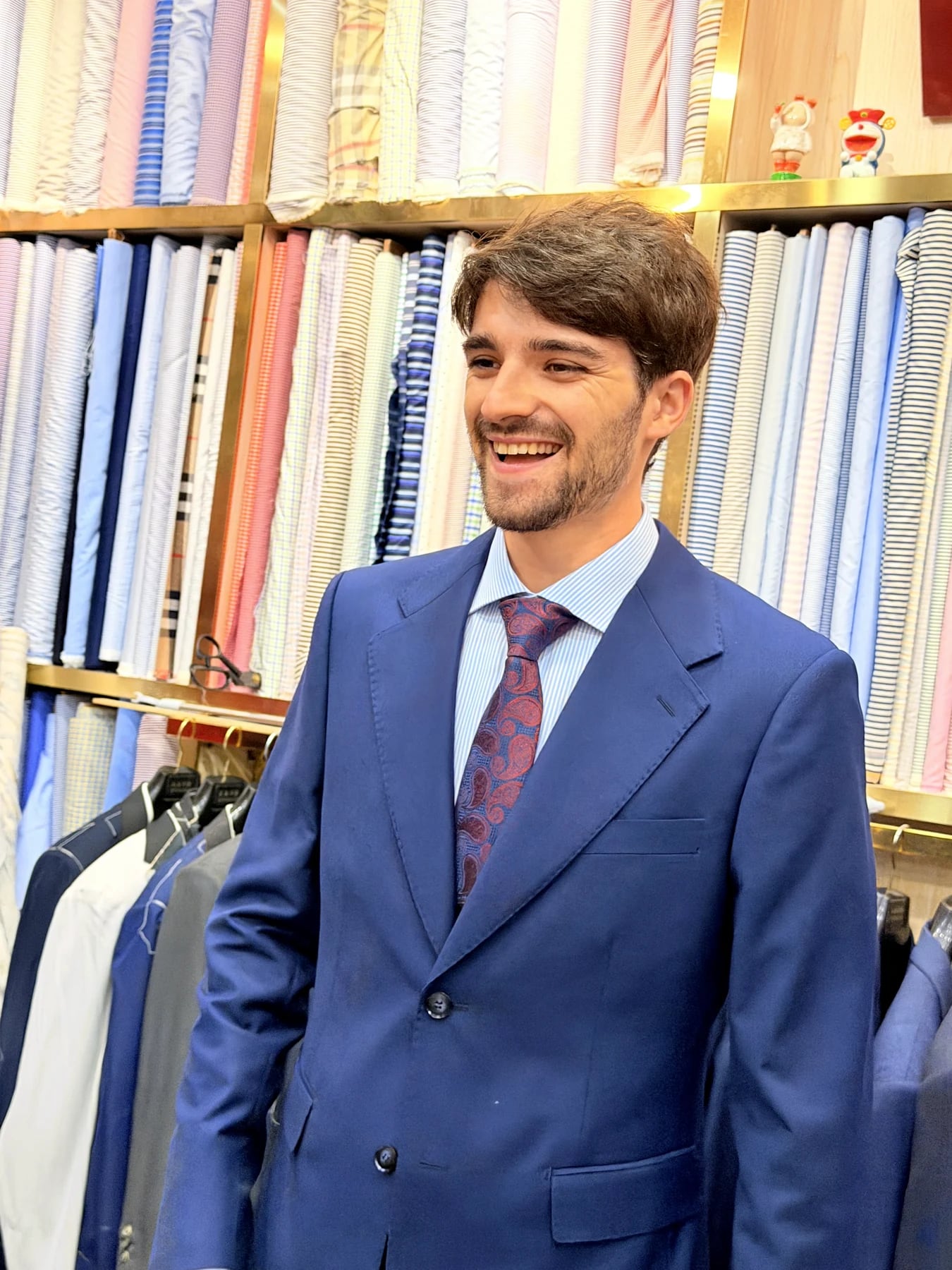 Three-quarter front view of a finished French blue suit with notch lapels and burgundy tie