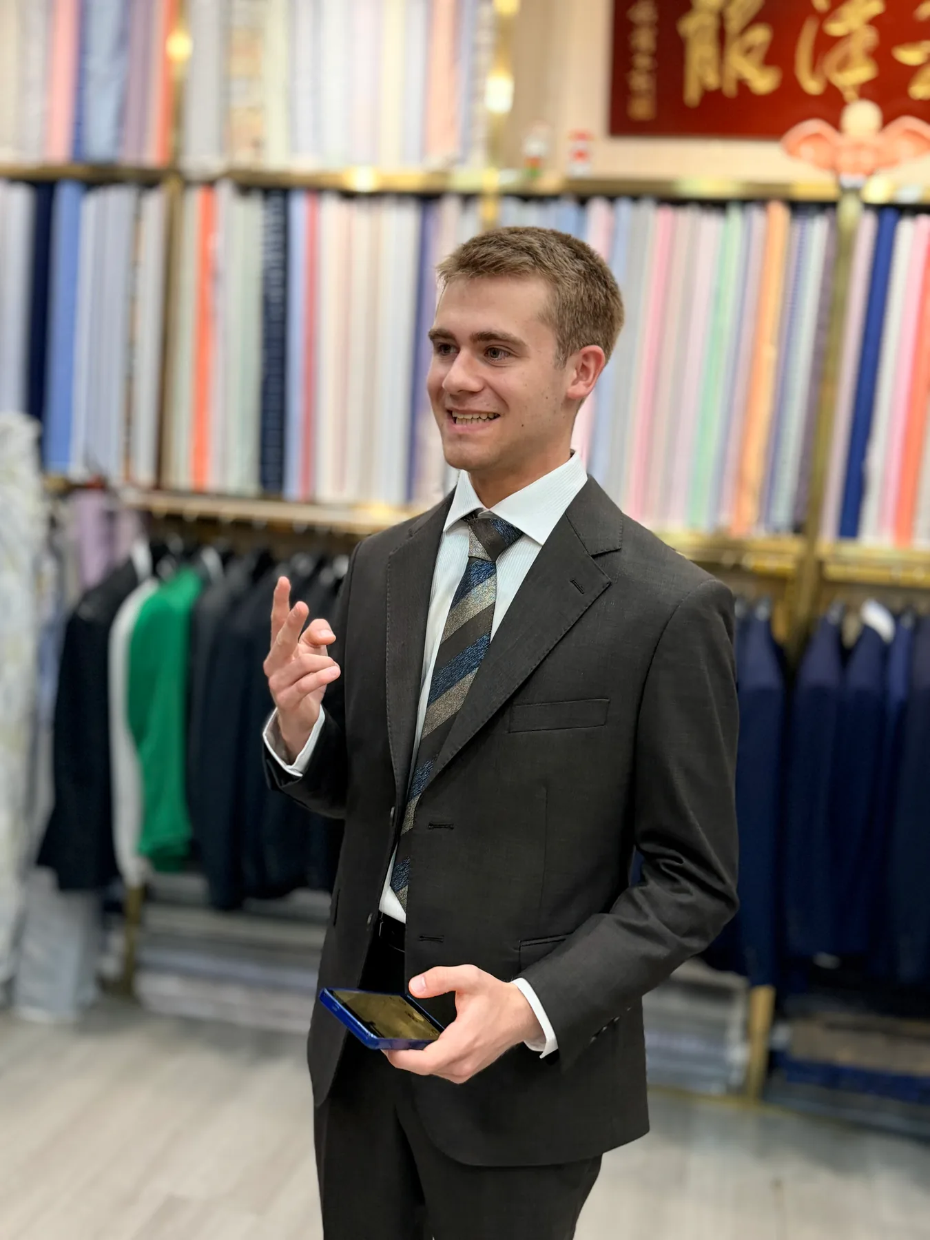 French student in a dark suit gesturing during an in-shop portrait at Wuyue