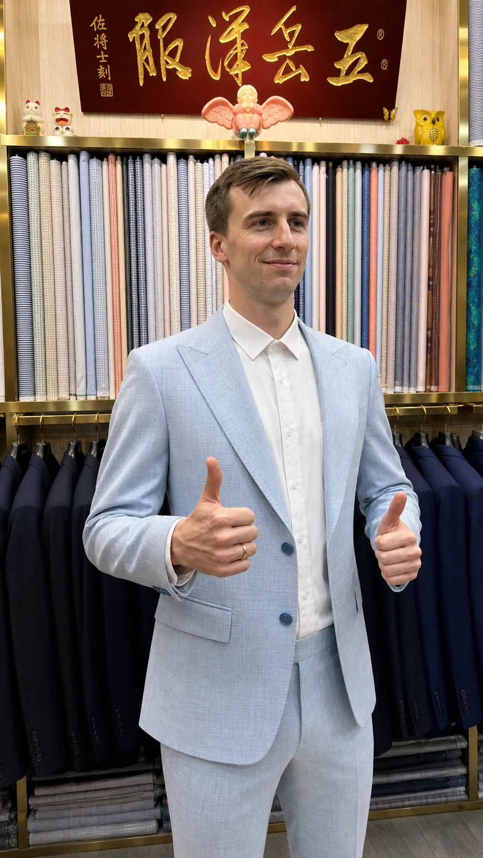 Client giving a thumbs-up while wearing a finished pale-blue suit at Wuyue