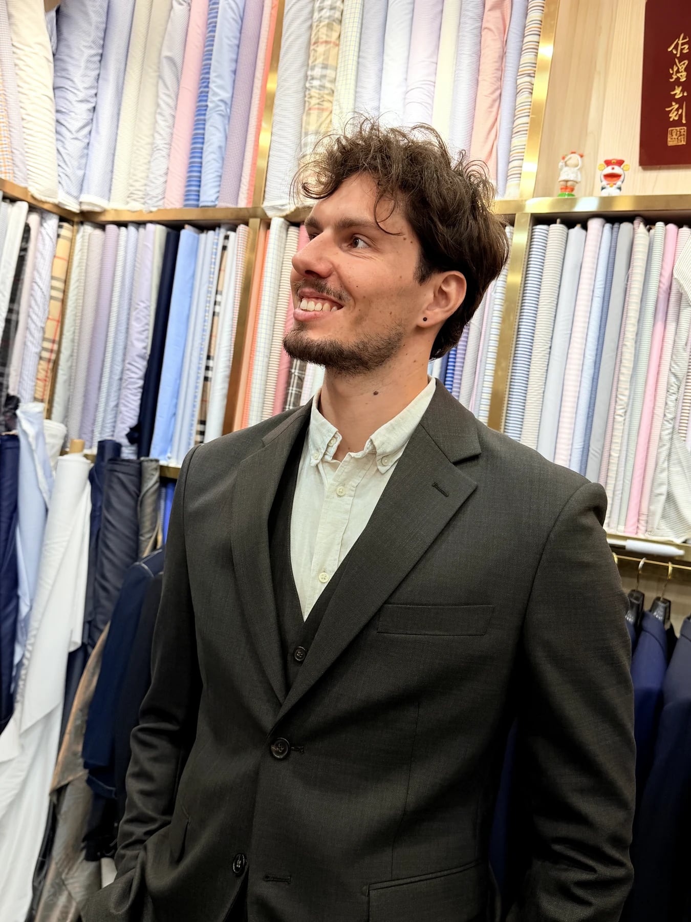 Upper-body portrait showing the notch lapel and shoulder of a grey three-piece suit