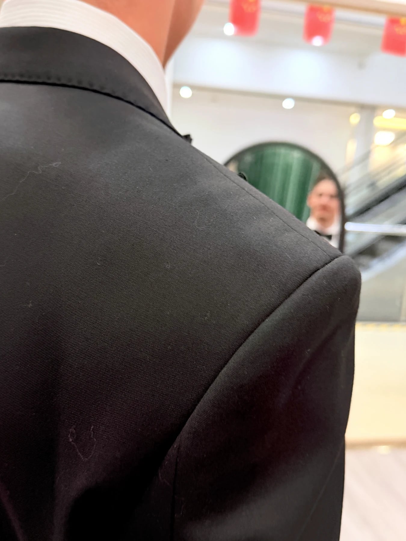 Close rear view of the shoulder and collar on a black tuxedo during a mirror check