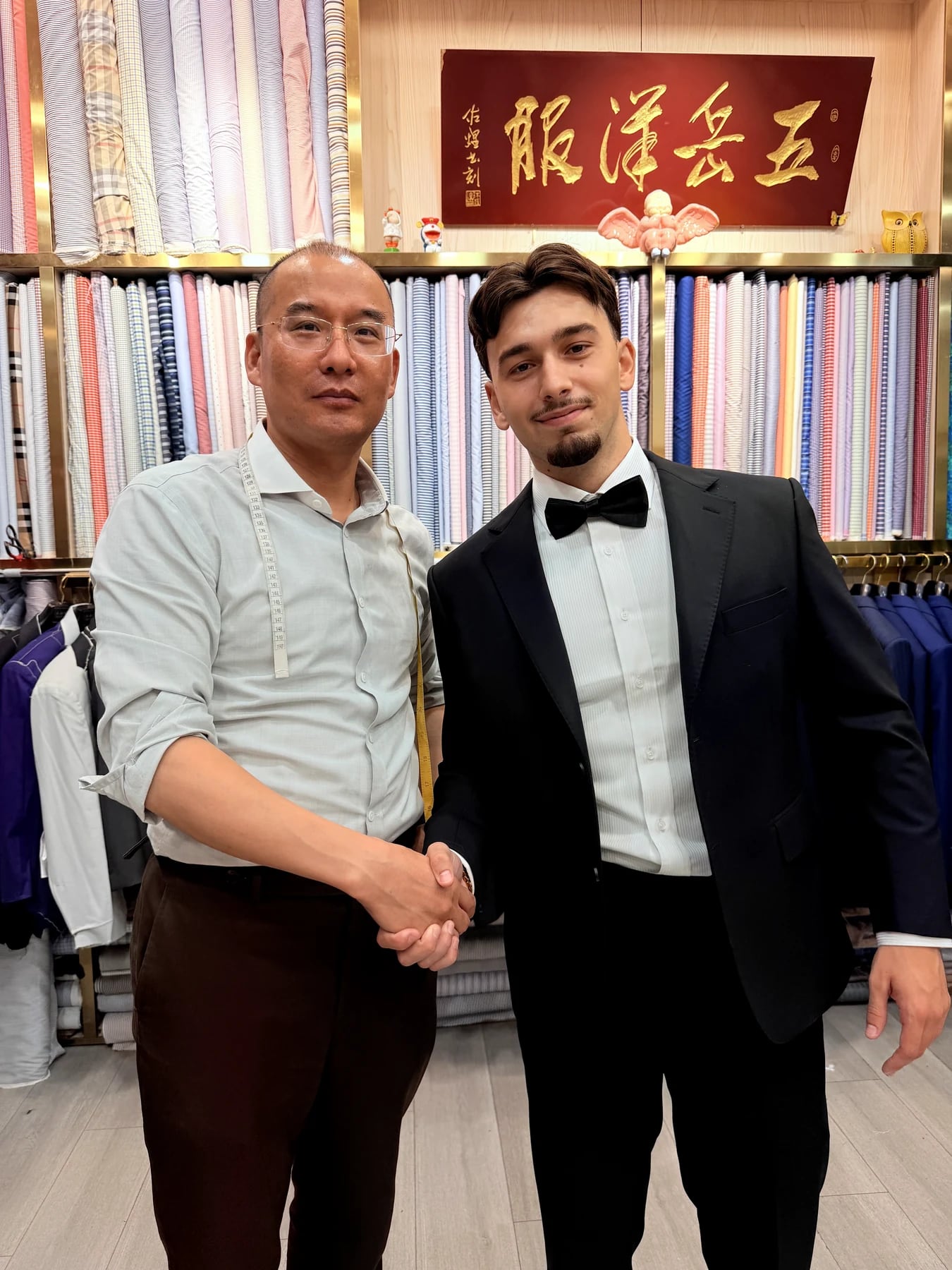 Client in a finished black tuxedo shaking hands with the Wuyue tailor