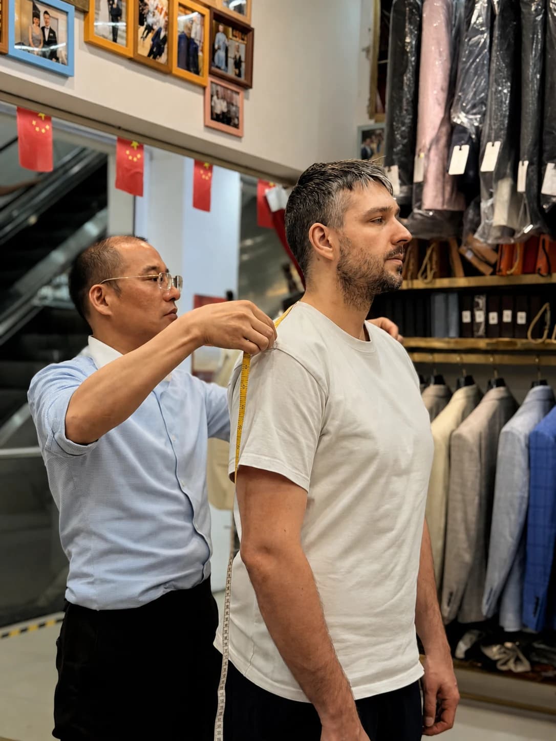 Wuyue tailor checking a client's shoulder balance during a custom suit appointment