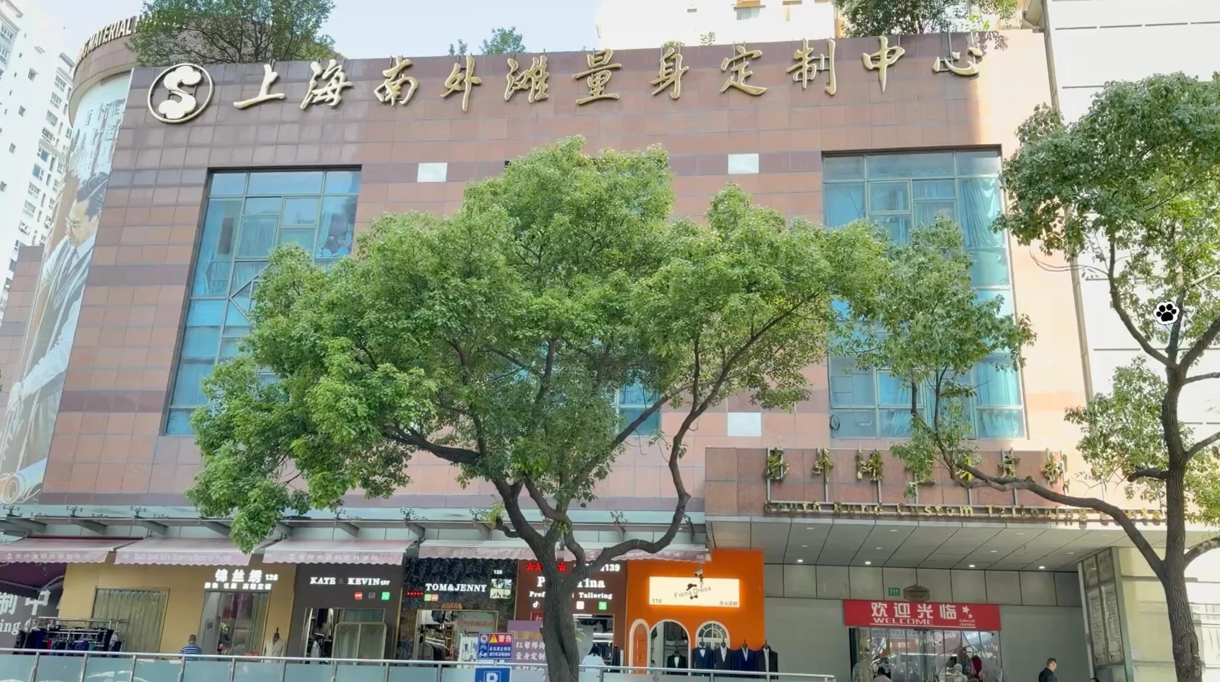 Exterior of Shanghai South Bund Fabric Market with the Chinese market sign above the ground-floor tailoring shops